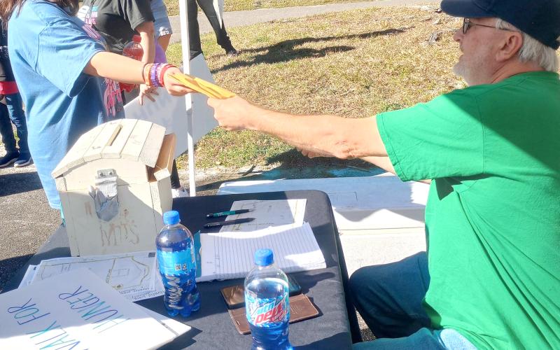 Callahan teen Dixie Conekin hands Be the Change Northeast Florida founder Joel Pace the pledges she raised for the inaugural Walk for Hunger Jan. 5.