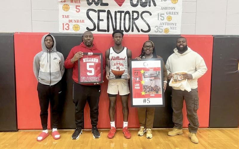 CJ Hall displays his 1,500-point basketball as he is honored Jan. 20. He is joined by his family, from left, Carlton Hall, Carlous Hall, Tasha Hall, and Leonard Smith. The Hilliard Middle-Senior High School athlete is in his final year of playing for the Flashes.