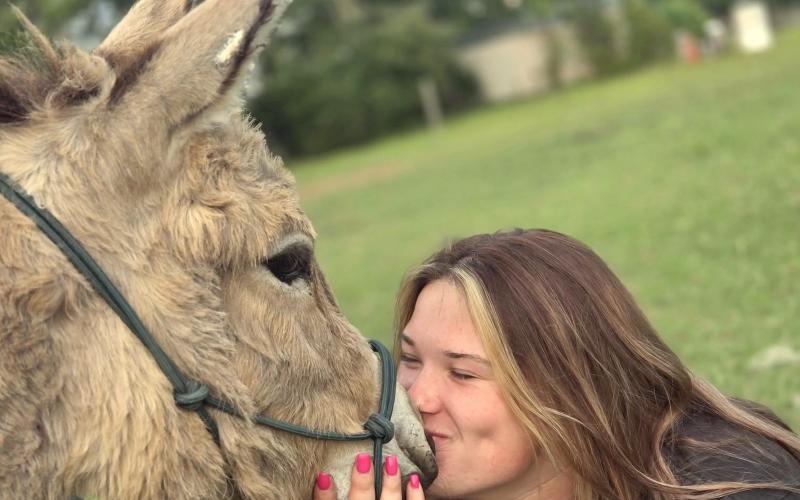 Taylor Bass  plants a kiss on Pickles from Burro Buddies. Burro Buddies is a donkey-drink delivery business in Nassau County.