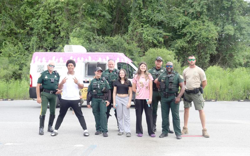 Callahan teenagers Robert Patterson, Kirra Nolen, and Destiney Browning stand with Nassau County Sheriff’s Office deputies at the NCSO’s ice pop patrol at Ewing Memorial Park in Callahan July 10.
