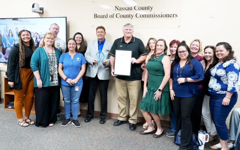 Keith Ellis, holding a proclamation about his service to the county, is joined by Nassau County Commissioner Jeff Gray and county employees and friends at the commission meeting Aug. 25. Submitted