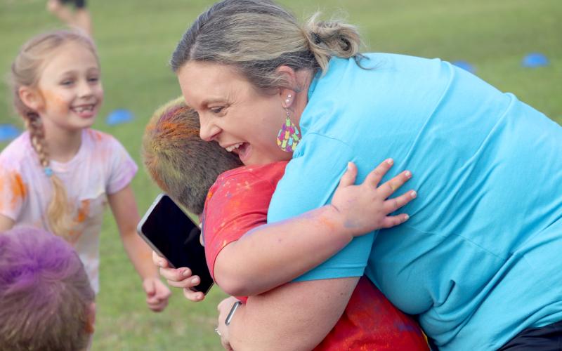 Callahan Elementary School ESE Support Facilitator Jessey Parm embraces kindergartner CJ Torres during the school’s Fun Run Friday morning. The Little Warriors raised more than $31,000, earning all students participation in the color run. Photo by Amanda Bishop