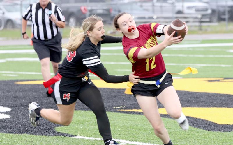 West Nassau's Payton Jefferson runs the ball as Hilliard's Lacey Vroman tries to pull a flag. The Lady Warriors shut out the Lady Flashes 28-0 April 6.