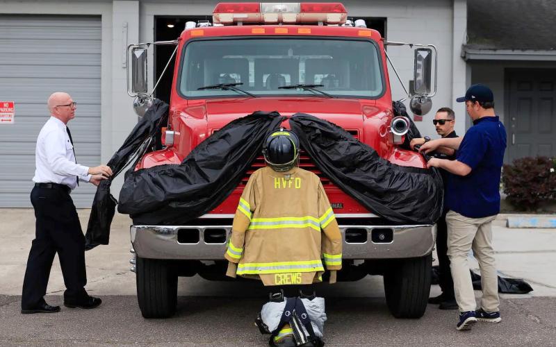 Hilliard Town Councilman Dallis Hunter works with Station 4 volunteer firefighters to adorn the town’s fire apparatus in memory of James “Kevin” Crews, whose funeral was held April 30. Photo by Alicia Head
