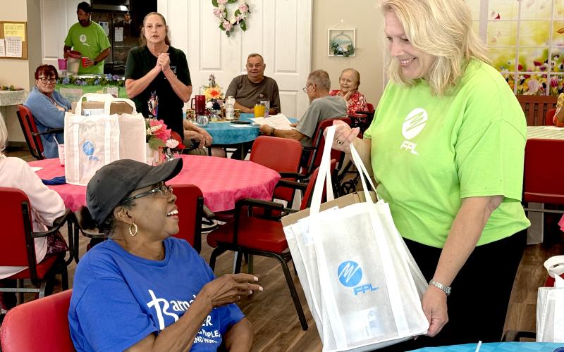 Hilliard resident Bernita Dinwiddie receives a meal kit from Carol Saviak, FPL external communications manager. The meal kits include shelf-stable items to assist senior citizens in the event of a power failure due to a storm.