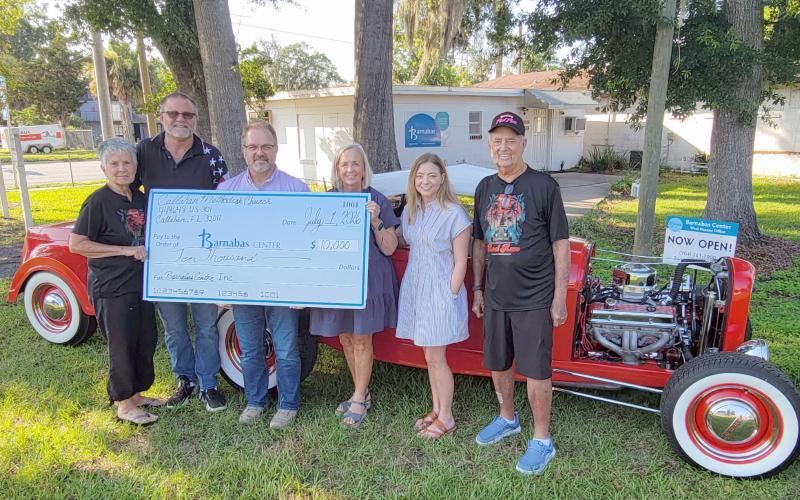 The annual Memorial Day Rod Run 4 Kidz, a mission of Callahan Methodist Church, raised $10,000 for Barnabas Center. Pictured left to right are Cheryl Mangold, Brad Mangold, Pastor Bodie Riddle, Barnabas President and CEO Jamie Reynolds and Community Engagement Manager Trish Thompson, and Jim Mangold. The annual fundraiser is held on the church grounds on the Saturday of Memorial Day weekend, drawing a crowd each year. Photo by Amanda Bishop