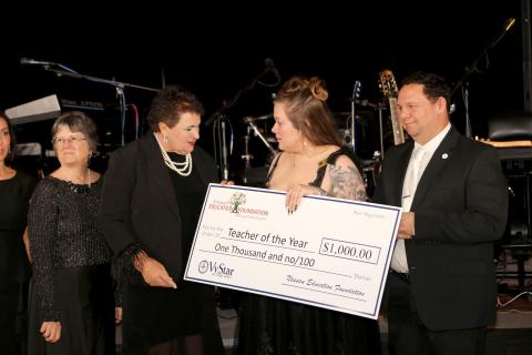 Callahan Intermediate School fourth grade teacher Kayla Hooper is the Nassau County Teacher of the Year. She accepts a ceremonial $1,000 check from Nassau County Schools Superintendent Kathy Burns as Nassau County School Board member Joe Zimmerman stands nearby at the Nassau Education Foundation Teacher of the Year Black and White Gala. 