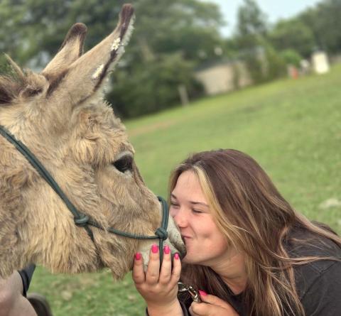 Taylor Bass  plants a kiss on Pickles from Burro Buddies. Burro Buddies is a donkey-drink delivery business in Nassau County.