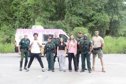 Callahan teenagers Robert Patterson, Kirra Nolen, and Destiney Browning stand with Nassau County Sheriff’s Office deputies at the NCSO’s ice pop patrol at Ewing Memorial Park in Callahan July 10. 
