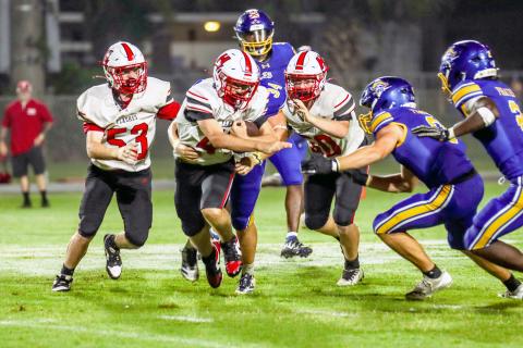Tucker Williams tucks the ball in close as he runs past Pirates, flanked by teammates Brock McPherson and Anthony Musgrove. 