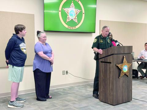 Nassau County Sheriff Bill Leeper speaks at the press conference Aug. 20 with victim Aaron Wiese and his mother, Amy Wiese, and Victim Advocate Madrina Addison nearby. Leeper warned parents to be vigilant about monitoring their children’s internet and social media activity. Photo by Anna Newhoff