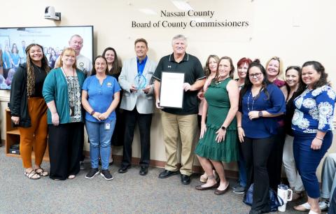 Keith Ellis, holding a proclamation about his service to the county, is joined by Nassau County Commissioner Jeff Gray and county employees and friends at the commission meeting Aug. 25. Submitted
