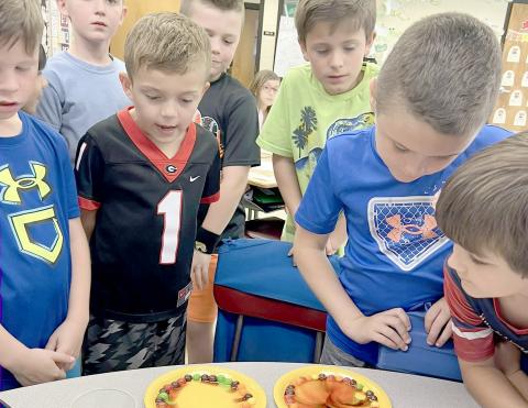 Hilliard Elementary School second grade students watch the colors of the rainbow melt off Skittles during a recent science experiment.