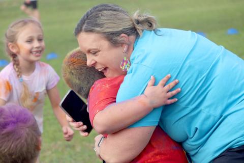Callahan Elementary School ESE Support Facilitator Jessey Parm embraces kindergartner CJ Torres during the school’s Fun Run Friday morning. The Little Warriors raised more than $31,000, earning all students participation in the color run. Photo by Amanda Bishop