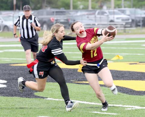 West Nassau's Payton Jefferson runs the ball as Hilliard's Lacey Vroman tries to pull a flag. The Lady Warriors shut out the Lady Flashes 28-0 April 6.