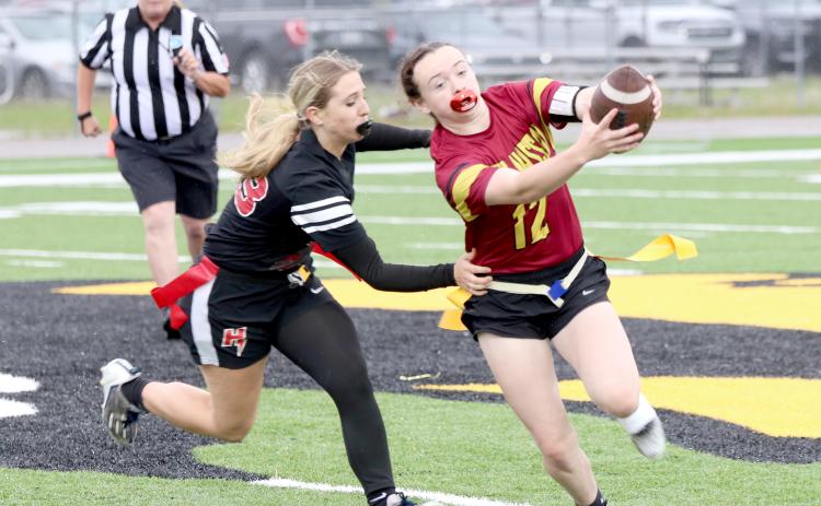 West Nassau's Payton Jefferson runs the ball as Hilliard's Lacey Vroman tries to pull a flag. The Lady Warriors shut out the Lady Flashes 28-0 April 6.