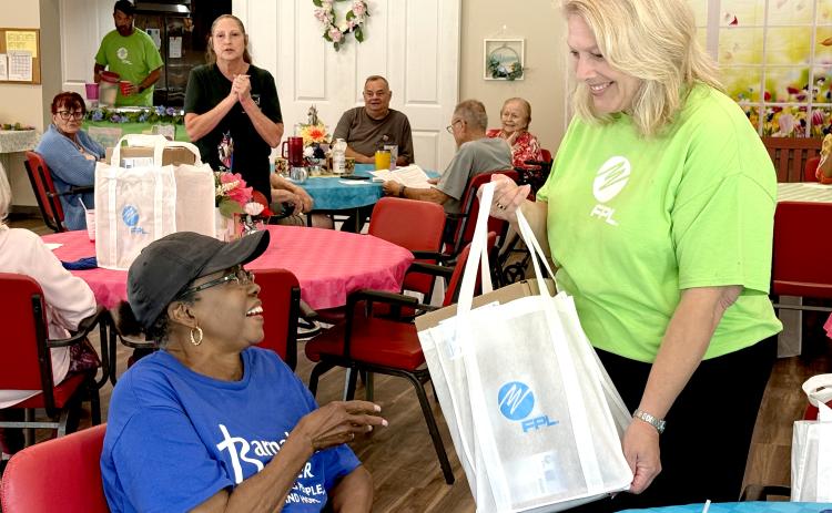 Hilliard resident Bernita Dinwiddie receives a meal kit from Carol Saviak, FPL external communications manager. The meal kits include shelf-stable items to assist senior citizens in the event of a power failure due to a storm.
